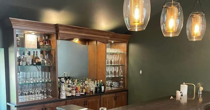 Freshly painted home bar with dark green walls and custom woodwork